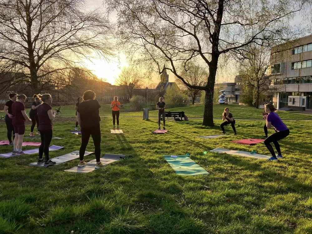 Groep vrouwen die buiten sporten op een grasveld bij zonsondergang in Ede
