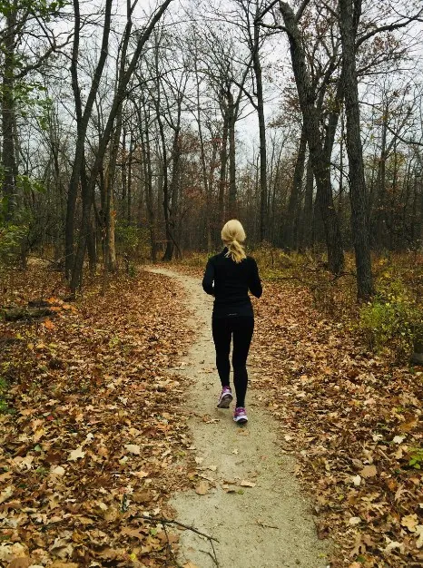 Vrouw hardloopt op een bospad in de herfst